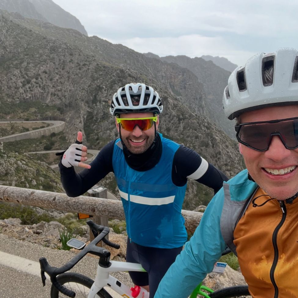 two men cycling on a highway in the mountains
